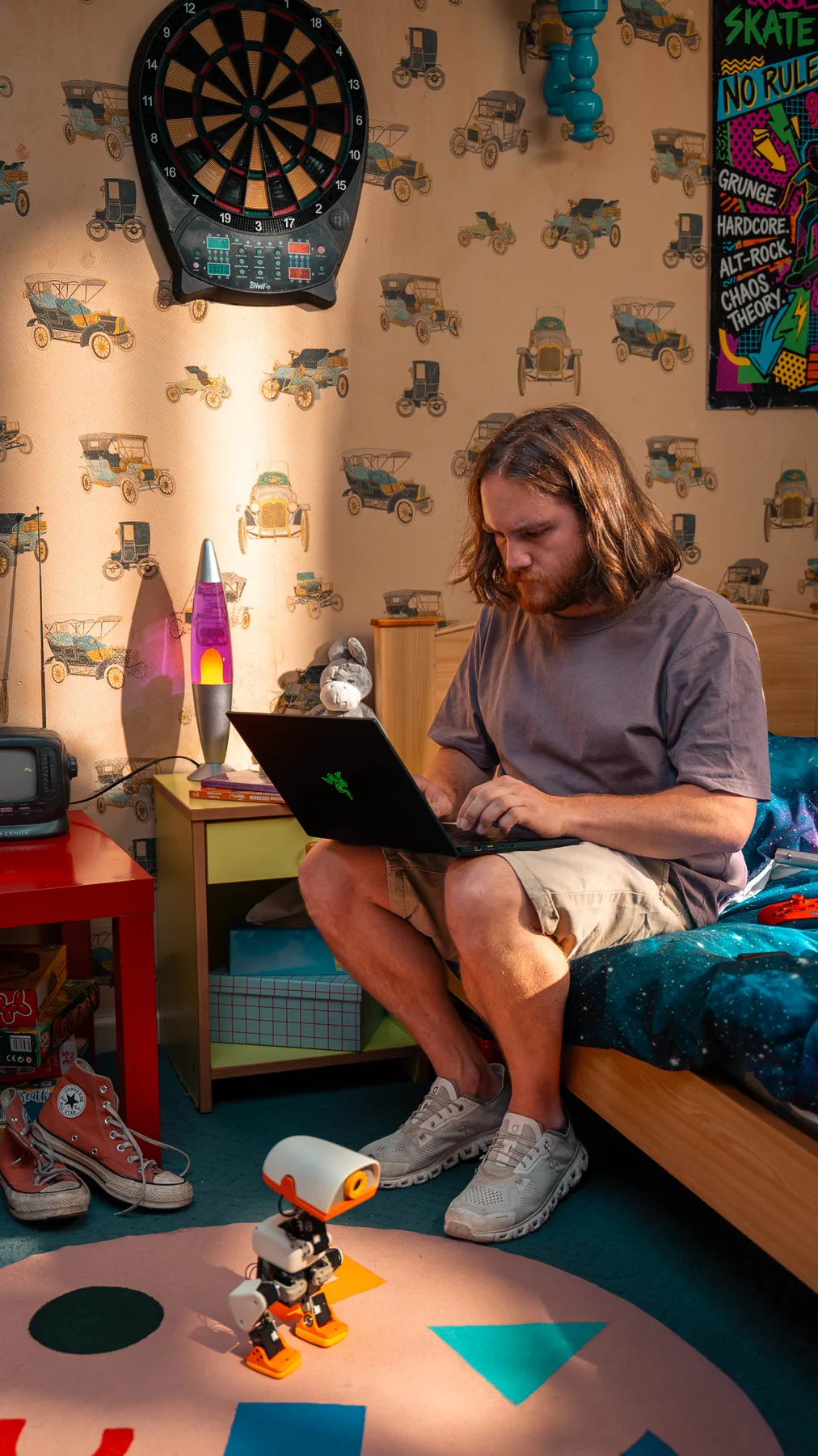 A MACRODUCK standing on a bedroom rug while its owner codes on the bed behind it